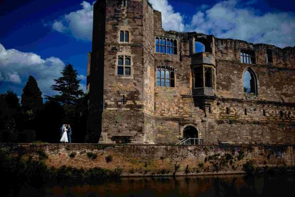 A wedding couple embracing each other next to Newark Castle
