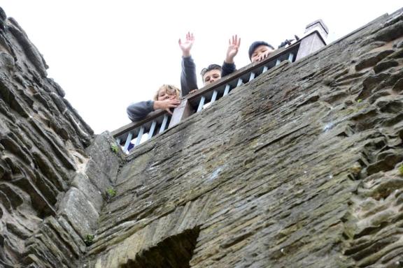 School children standing at the top of the Newark Castle tower with their arms in the air
