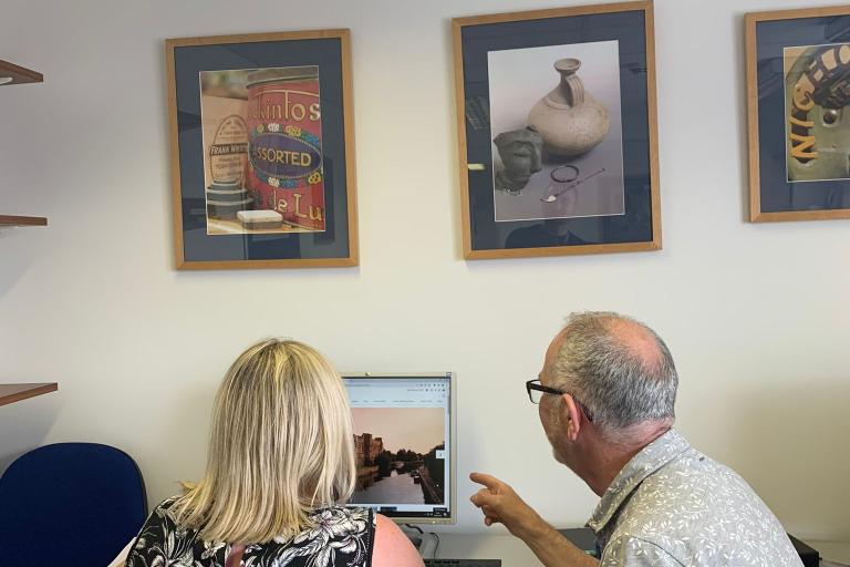 Two Newark Castle researchers facing a computer screen talking and working