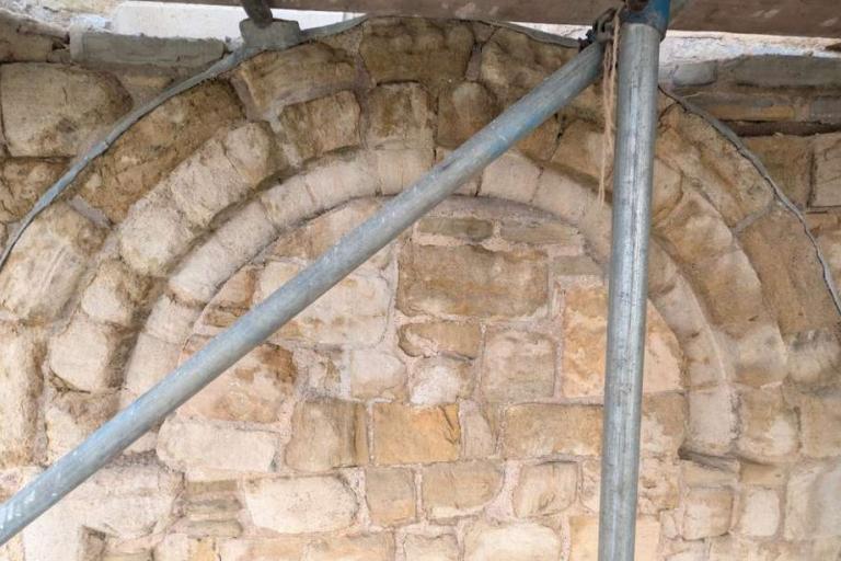 Eroded Norman Romanesque stone window arch within scaffolding on the Gatehouse.