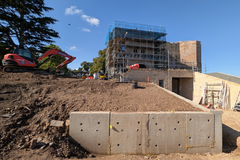Construction on castle gatehouse in the background with mound of mud landscaping held back by wall