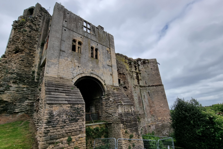 Historic stone castle gatehouse with weathered walls and an arched entrance beneath a cloudy sky.