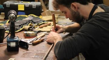 Student working on medieval instrument on woodwork table