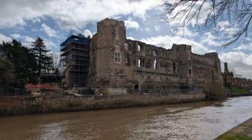 Riverside view of Newark Castle curtain wall showing a sequence of historic openings in the stonework.