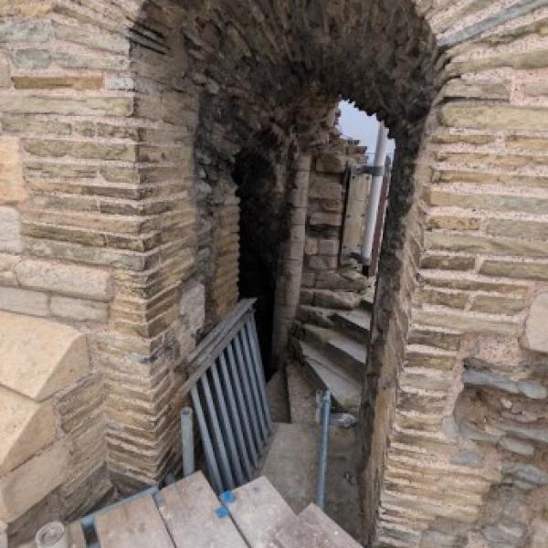 Stone arch above the spiral staircase inside the Gatehouse, leading onto the new viewing area, with scaffolding and steps visible below.